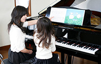 シェルター内でピアノレッスンを行う先生と生徒